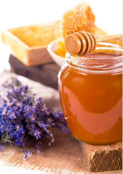 Photo d'un pot de miel de lavande avec une cuillère de miel et une feuille de lavande à côté.